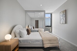 Un dormitorio moderno con cama, mesita de noche y un amplio ventanal.