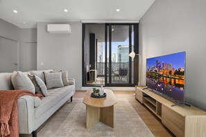 Una sala de estar moderna con sofá, mesa de centro y televisor.