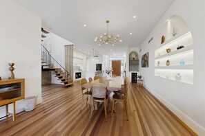 A spacious dining area with a wooden floor, a central table, and wicker chairs. - Spacious 5-Bed Stay Near Mandurah (Wannanup)