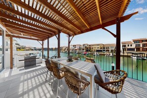 A covered outdoor dining area with a view of a marina and buildings. - Spacious 5-Bed Stay Near Mandurah (Wannanup)