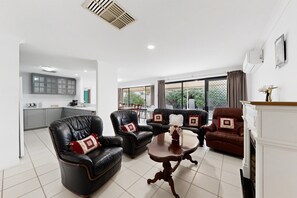 A modern living room with leather sofas, a wooden coffee table, and a kitchen in the background.