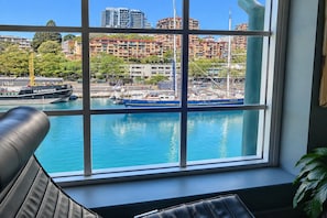 Blick aus einem Fenster auf einen Yachthafen, Boote und Gebäude im Hintergrund.