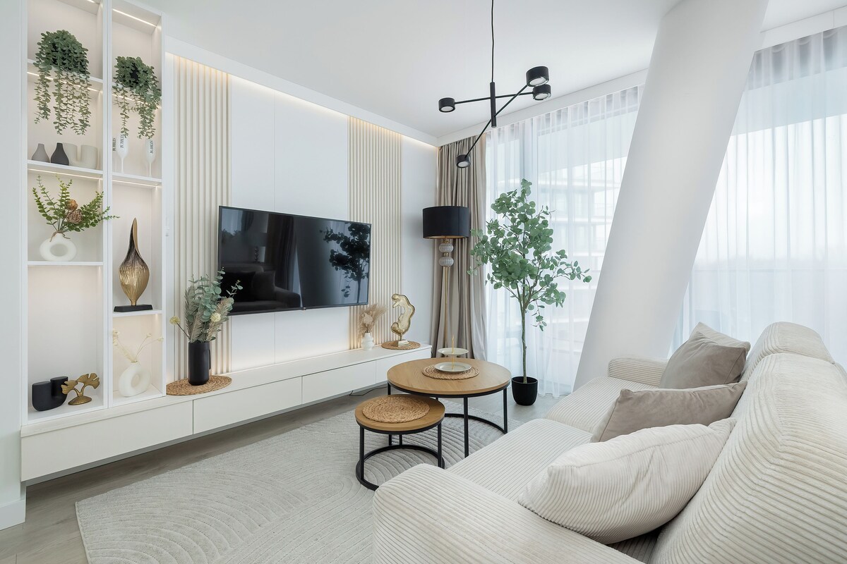 Ein modernes Wohnzimmer mit Sofa, Fernseher, Esstisch und Dekorationselementen.