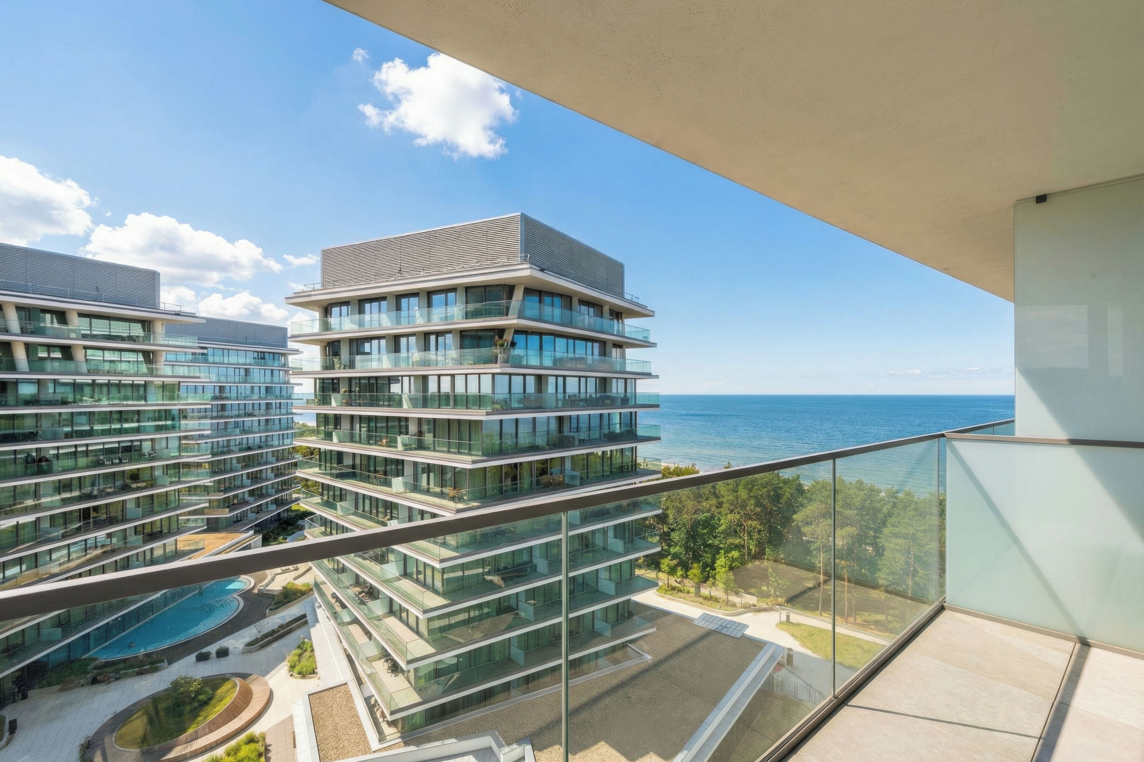 A high-rise building with multiple balconies overlooking a pool and ocean view.