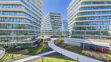 Un edificio moderno de varios pisos con fachada de vidrio, un patio central y un sendero curvo.