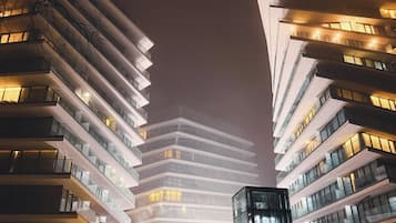 Un edificio moderno con varios pisos y balcones, que presenta una entrada central con escalones que la conducen.