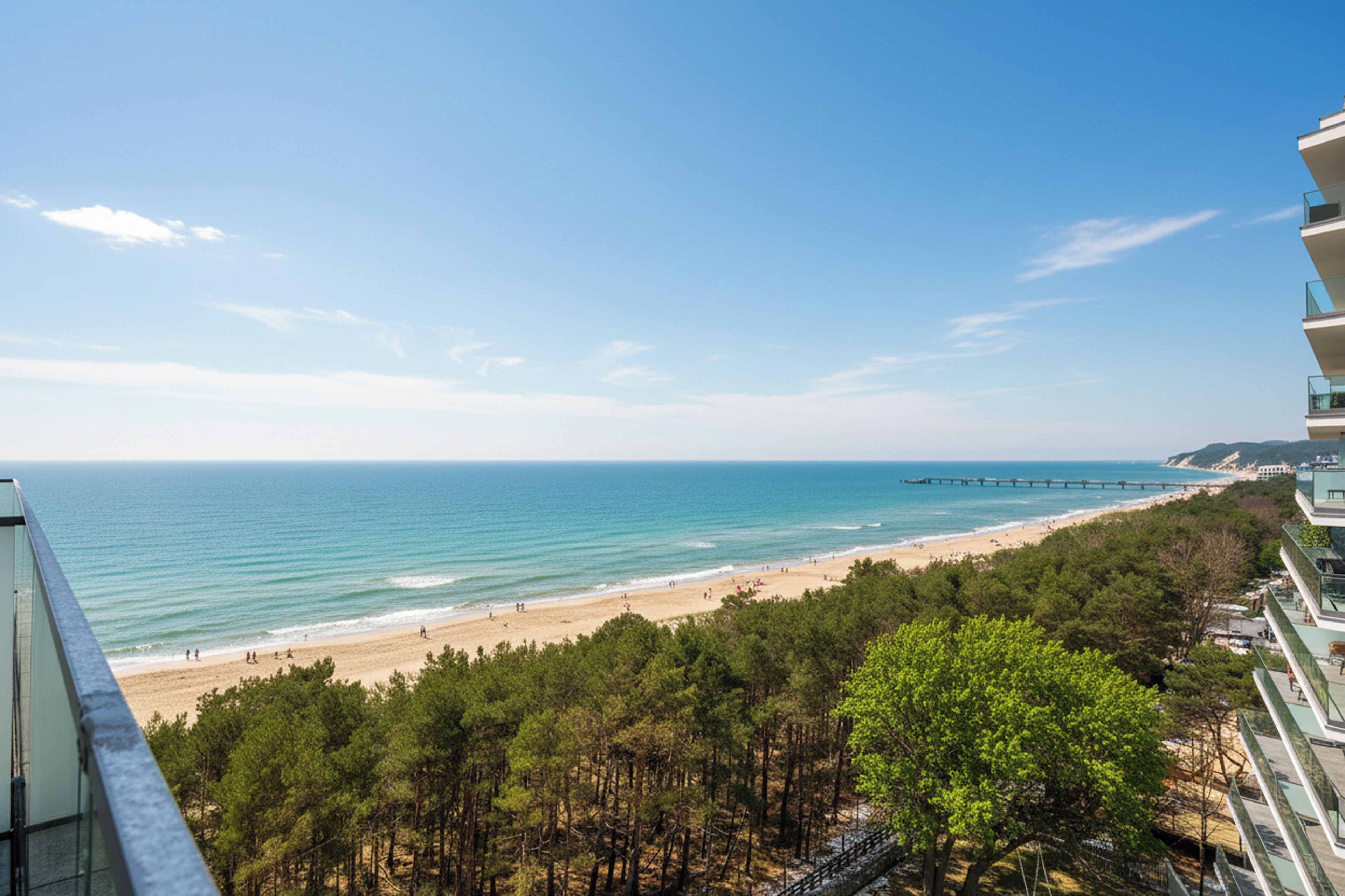 Une vue côtière comprenant une plage, l’océan et une zone boisée.