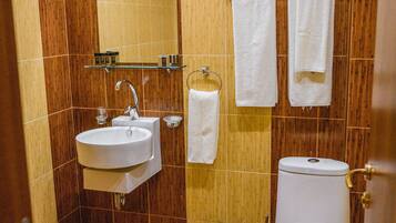 Un baño con lavamanos, espejo, toallero y inodoro.