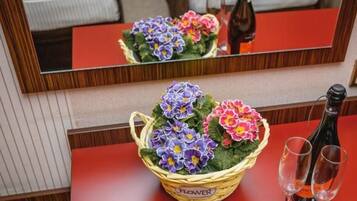 Una habitación de hotel con cama, espejo, mesa y una cesta de flores, además de dos vasos.