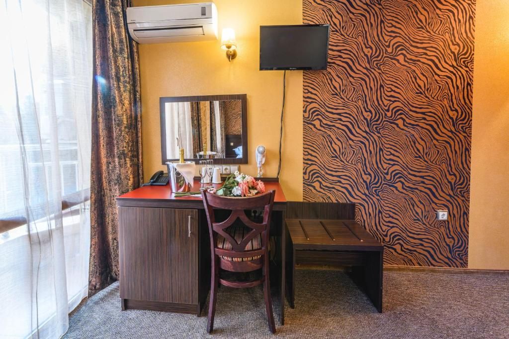 Una camera d'albergo con una scrivania, una sedia e un televisore a parete.