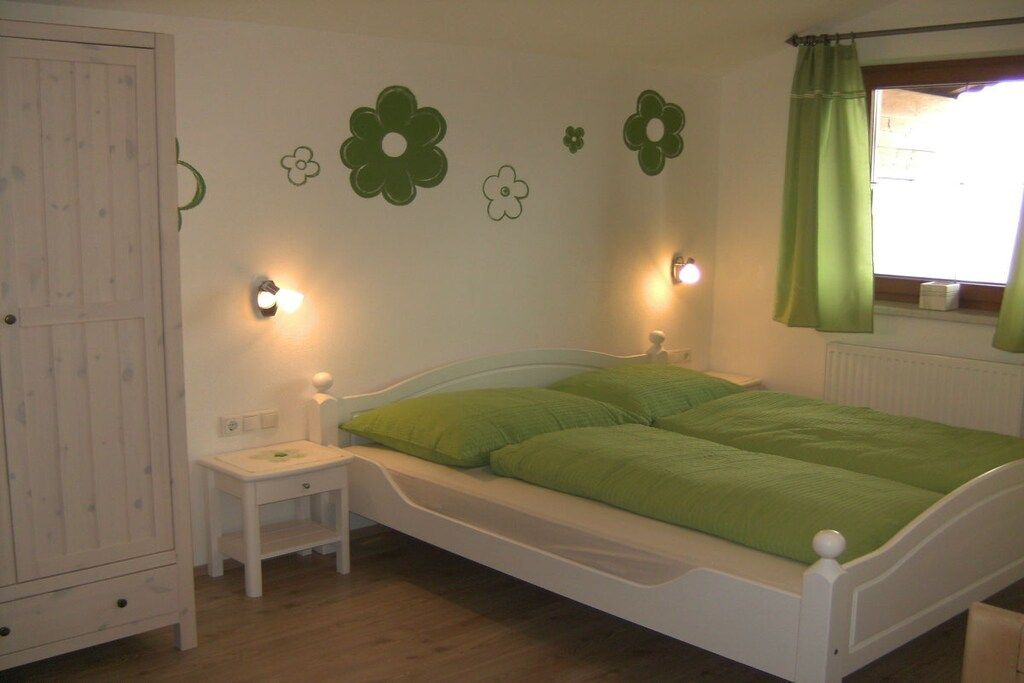 A bedroom with a bed, bedside table, and wall decorations.