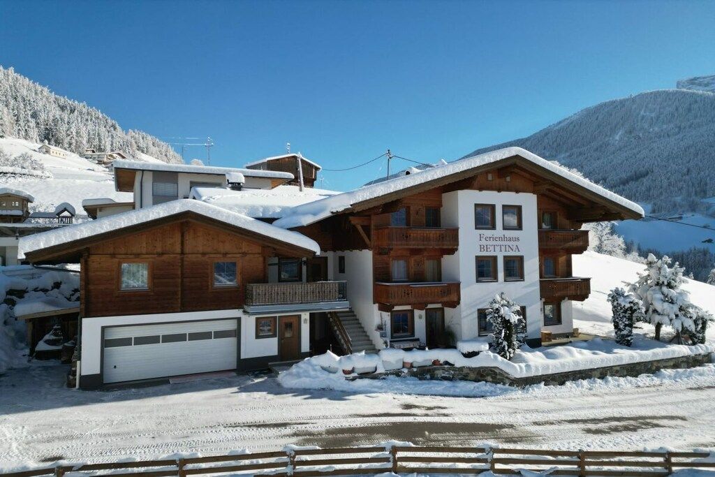 A chalet-style hotel with a wooden facade, a visible garage, and a sign indicating the name 'Ferienhaus BETHINA.'