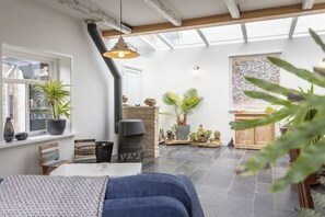 A cozy living area with a fireplace, potted plants, and a view of the outdoors. - Holiday apartment with 2 bedrooms (Oudeschild)