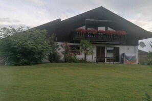 Ein zweistöckiges Haus mit Balkon, überdachter Eingangstür und Rasenfläche.