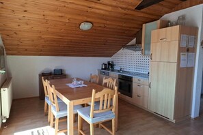Eine kleine Küche mit Holzausstattung, einem Esstisch mit Stühlen und einem kleinen Kühlschrank.