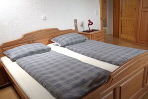 Ein Doppelbett mit Holz Kopfteil, zwei Kissen, ein Nachttisch mit Lampe und ein Holzschrank.