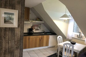 Eine Küche mit Holdekor, einer weißen Arbeitsplatte, einem Spülbecken und einem Essbereich mit Tisch und Stühlen.