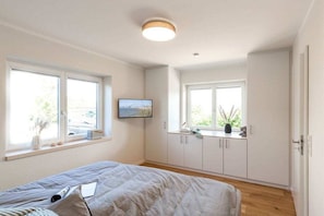 Ein Schlafzimmer mit einem Bett, einem Fenster, einem Fernseher und einem Schrank.