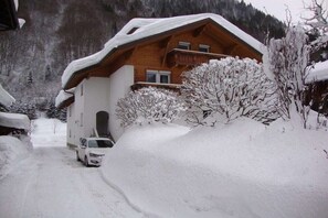 Ein mit Schnee bedecktes Holzhaus mit einem geparkten Auto davor.
