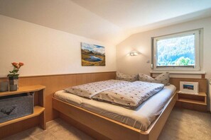 A bedroom with a bed, bedside tables, a window with a view, and a wall-mounted picture. - Holiday apartment with 1 bedroom (Gortipohl)