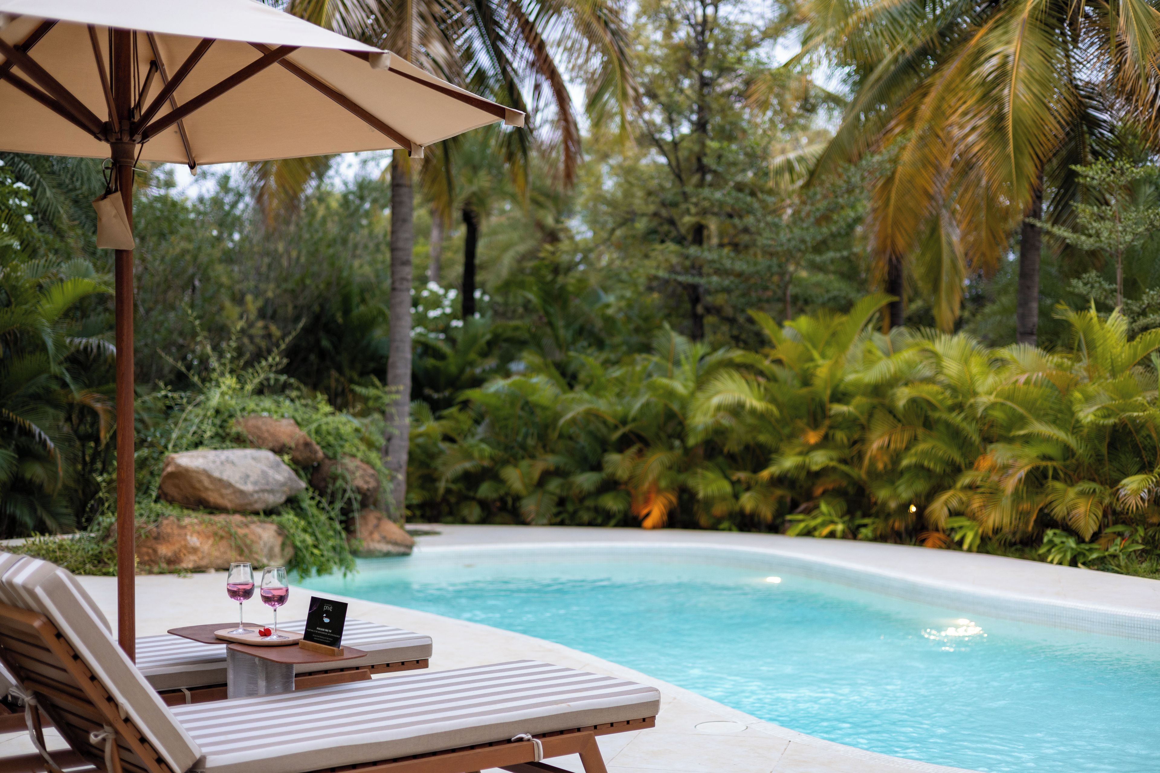 A poolside area with lounge chairs and a table with glasses and a menu.
