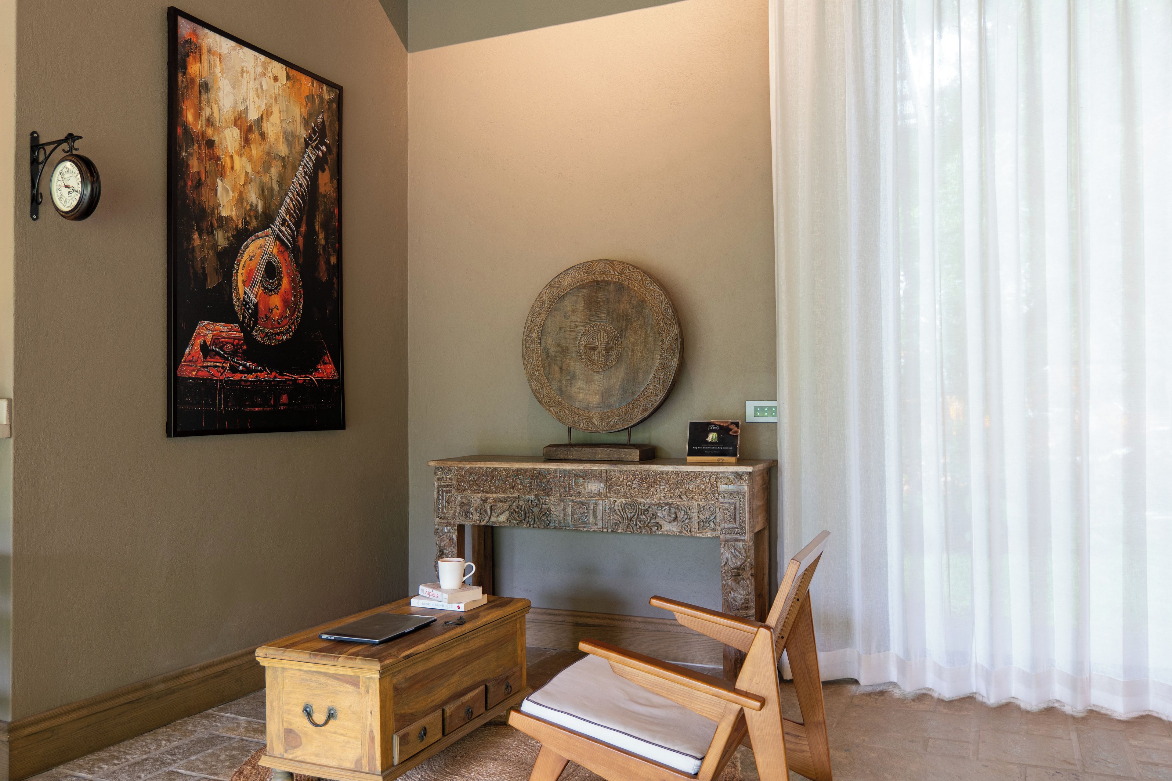 Una habitación con un cofre de madera, una silla, un reloj en la pared, un plato decorativo y una obra de arte enmarcada.