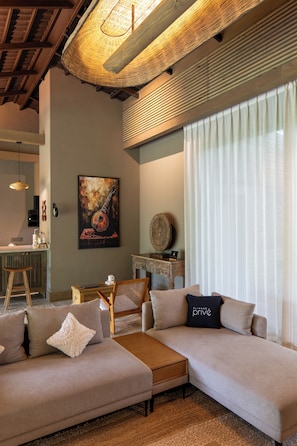 A modern living room with a sectional sofa, a coffee table, and a dining area with a chair and table.