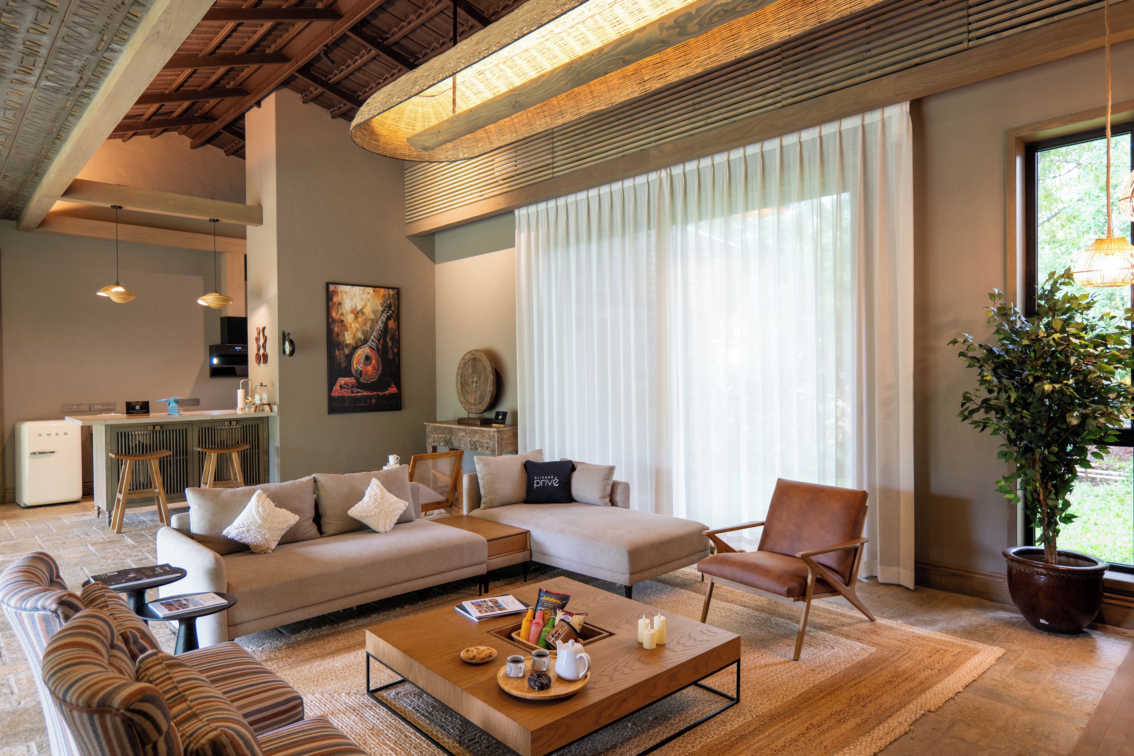 Ein modernes Wohnzimmer mit Sofa, Sessel, Couchtisch und einem Essbereich mit Bar.
