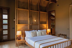 A hotel room with a large bed, two bedside tables, a wooden headboard, a built-in shelf, and a door with glass panels.
