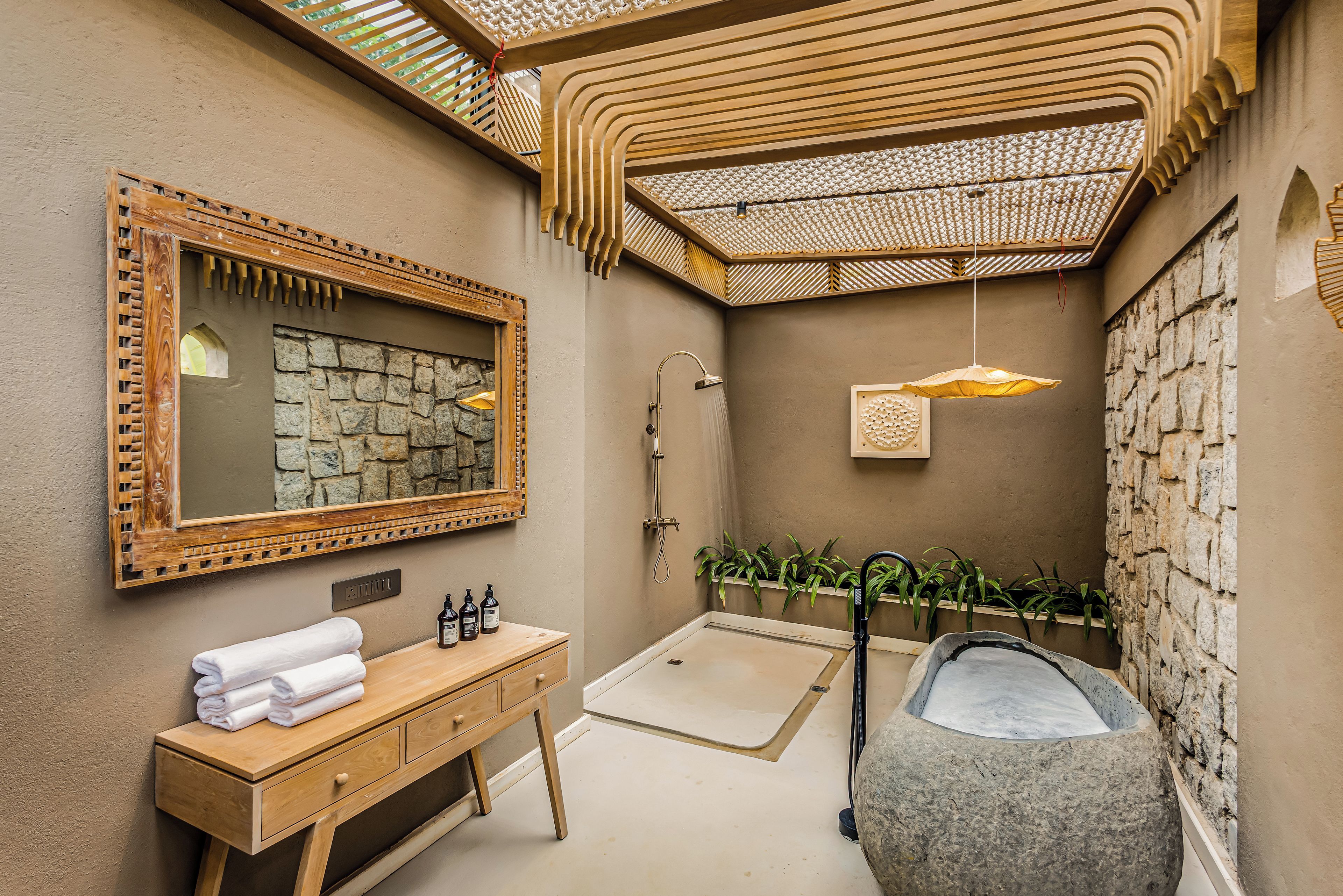 Un baño con tocador de madera, lavamanos de piedra, ducha y bañera de piedra.