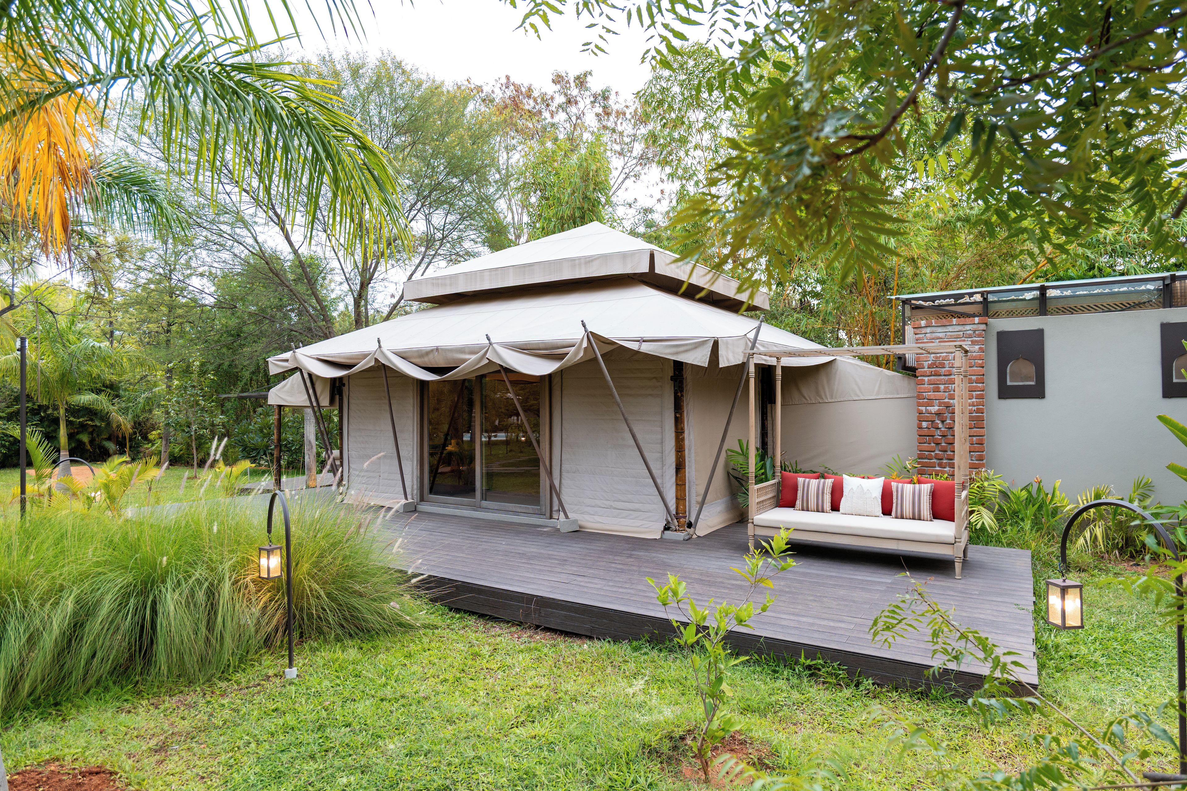 A small, single-story building with a covered porch and a seating area with cushions.
