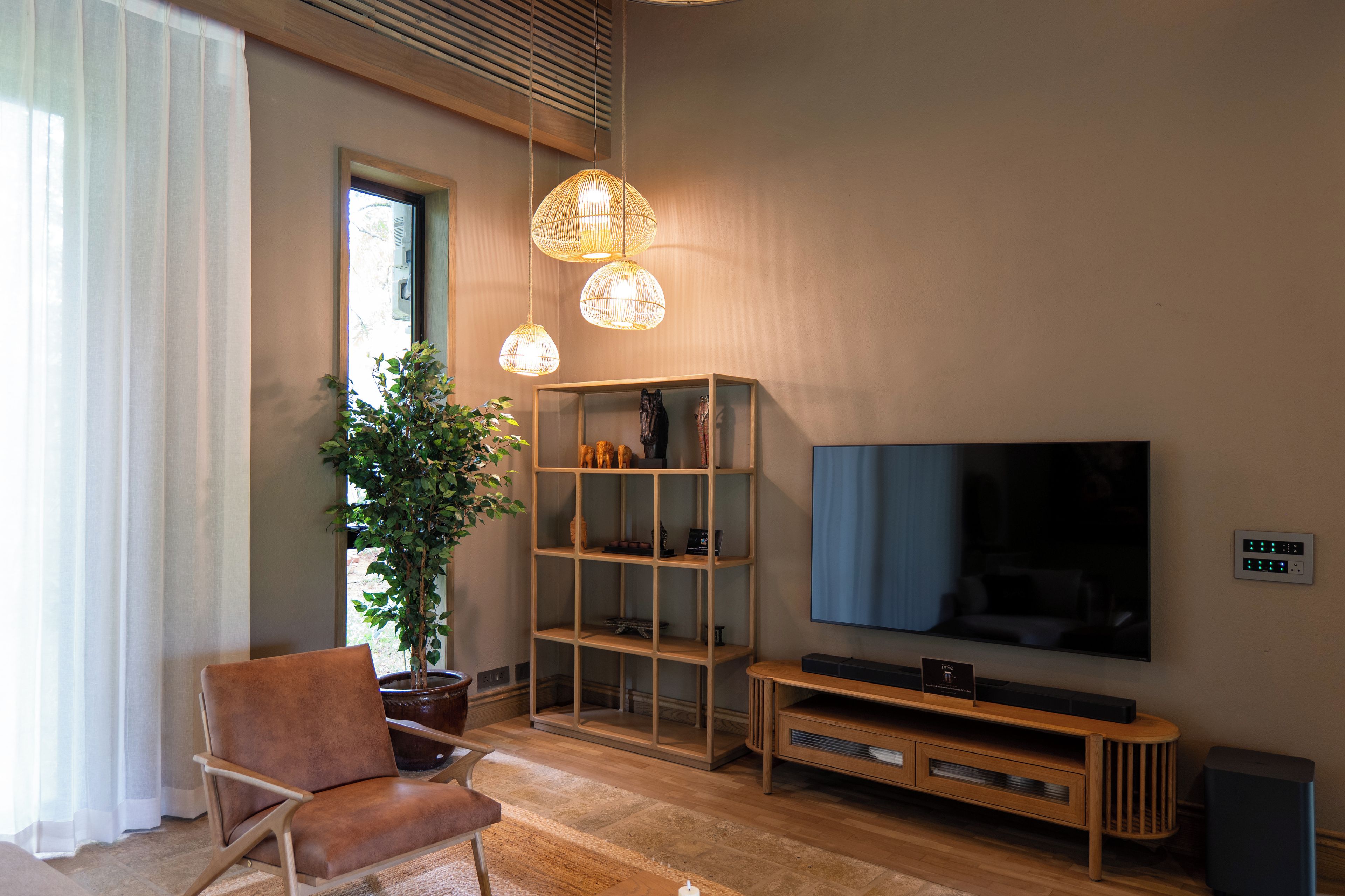 Una sala moderna con un televisor de pantalla plana grande, un sillón de cuero marrón, un mueble de entretenimiento de madera y una planta en maceta.