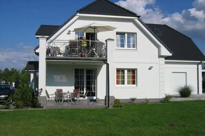 A two-story house with a balcony, a covered outdoor seating area, and a garage. - Villa Guta, Apartment 2 (Rowy  Polen)