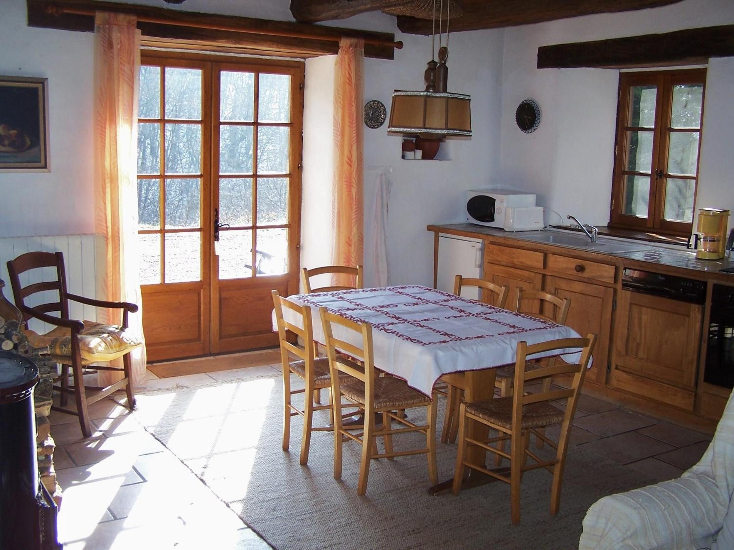 Eine gemütliche Küche mit Holdekor, einem Esstisch mit Stühlen, einem Fenster mit Vorhängen und einer Pendelleuchte.