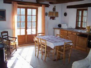 Una cucina accogliente con mobili in legno, un tavolo da pranzo con sedie, una finestra con tende e un lampadario.