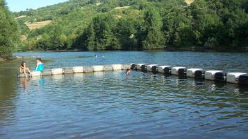 Un lago con una fila de barreras de hormigón y dos personas sentadas al borde.