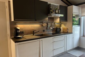 A modern kitchen with a black countertop, white cabinets, and a built-in oven. - Holiday home Chateau Briand (De haan)