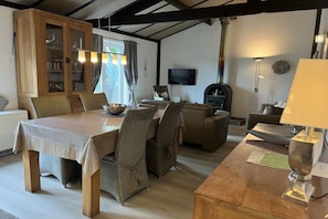 A dining area with a table and chairs, a sofa, a television, and a fireplace. - Holiday home Chateau Briand (De haan)