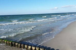 A beach with waves, a wooden jetty, and a clear sky. - Holiday apartment with 1 bedroom (Gelbensande)