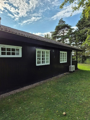 Un bâtiment noir avec des fenêtres à encadrement blanc et un petit appareil de climatisation sur le côté.