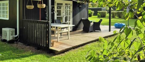 A house with a deck, outdoor furniture, and a lawn.