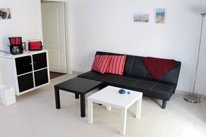 A living room with a sofa, two coffee tables, a cabinet, and a floor lamp. - Holiday apartment with 2 bedrooms (Ostseebad Rerik)