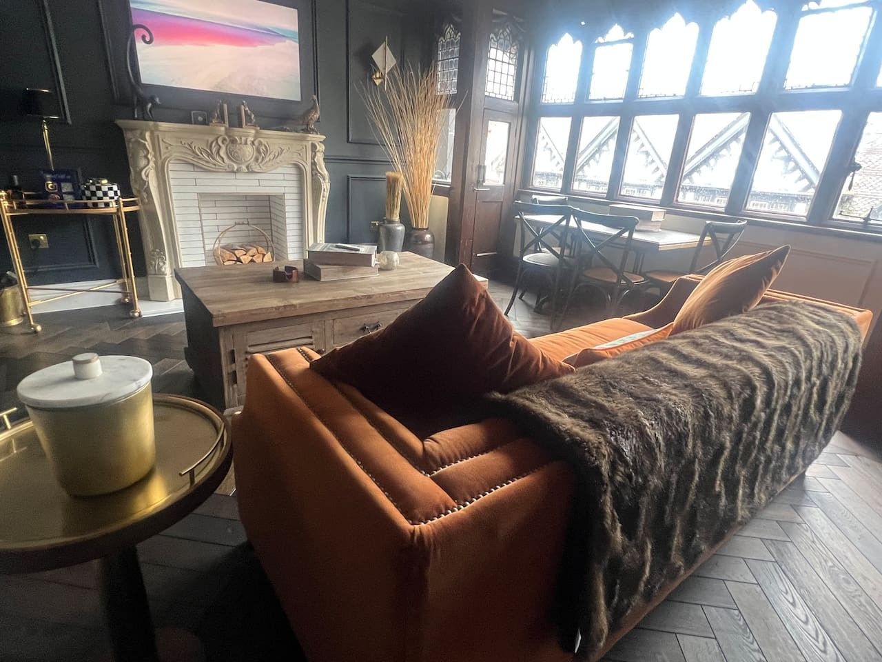 A living room with a sofa, a fireplace, a television, and a view through large windows.