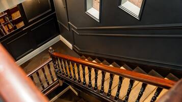Un escalier avec des balustrades en bois et un mur sombre agrémenté d’une fenêtre.