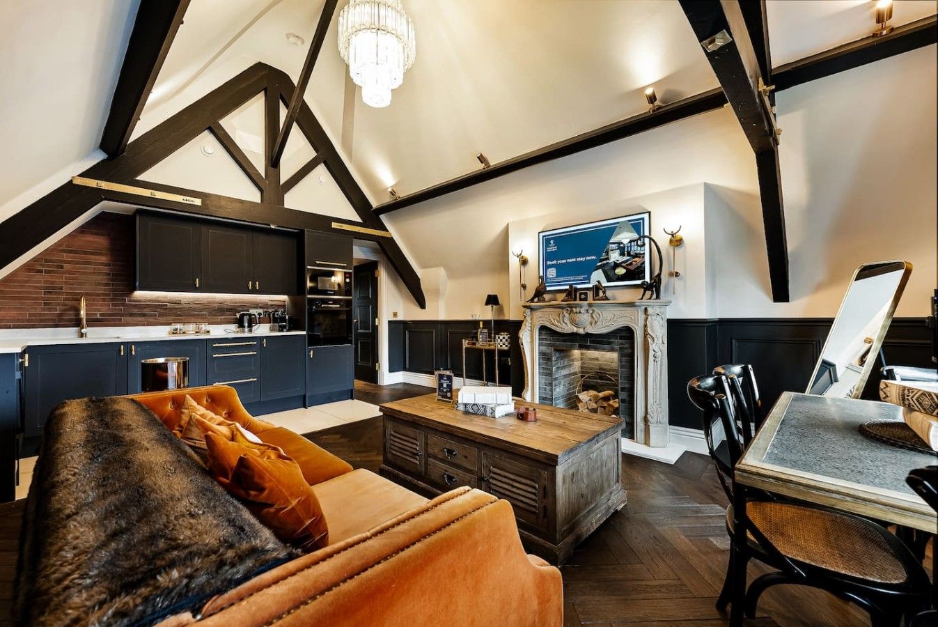 Ein großzügiges Loft mit hohen Decken, freiliegenden Balken, einem Kamin, einem Fernseher und einer gemütlichen Sitzecke.