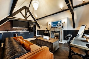 Ein großzügiges Loft mit hohen Decken, freiliegenden Balken, einem Kamin, einem Fernseher und einer gemütlichen Sitzecke.
