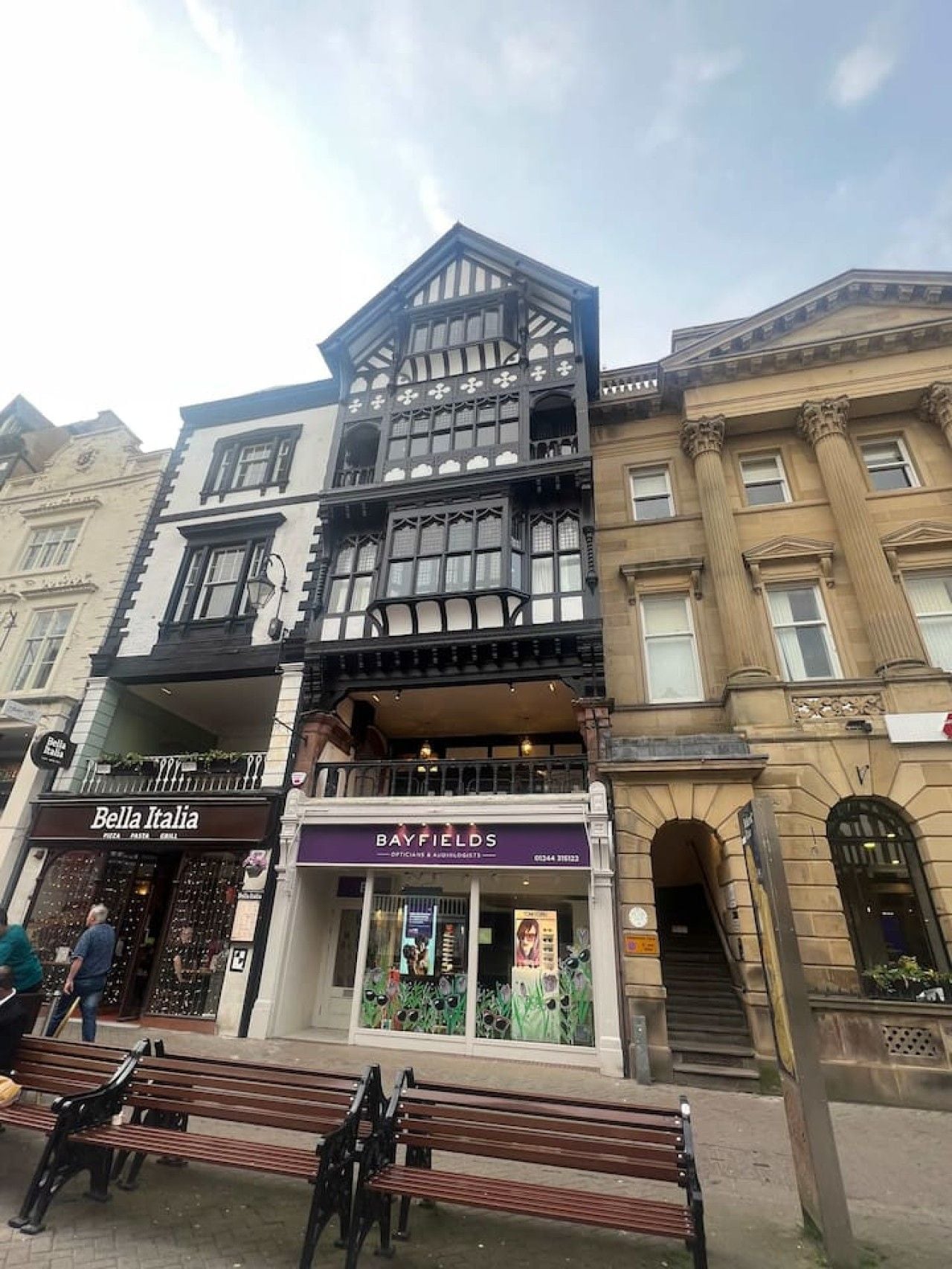 A multi-story building with a ground-floor shop named 'Bella Italia' and a second-floor shop called 'Bayfields.'