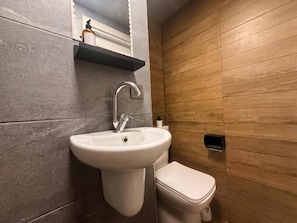 A bathroom with a white sink, a toilet, and a wooden wall. - Köşk Butik Otel (Antalya)