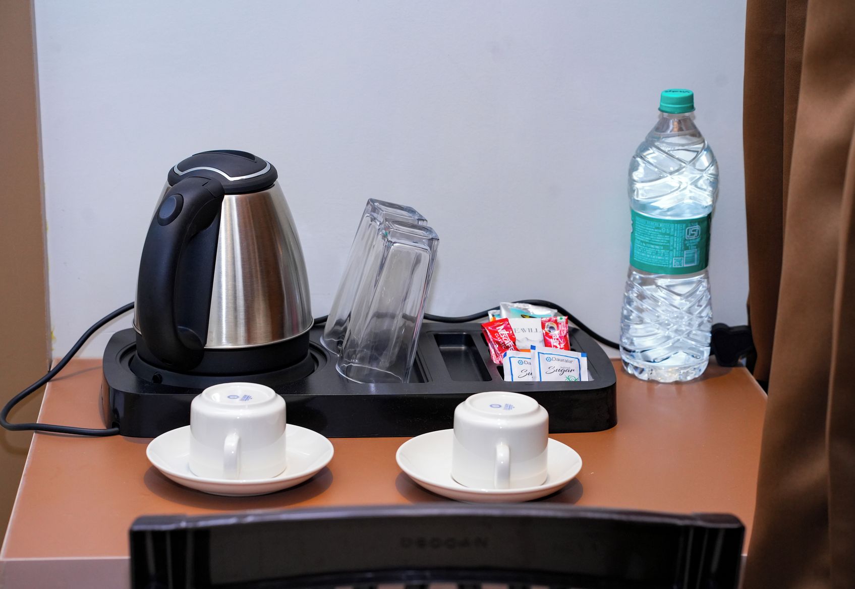 Une machine à café, une bouteille d’eau et deux tasses sur une table.