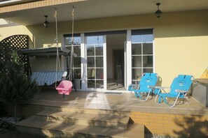 A covered patio with a swing, two lounge chairs, and a sliding glass door leading to an interior space. - Holiday apartment with 4 bedrooms (Grzybowo)
